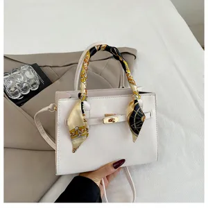 Detailed shot of trendy women leather handbag with twilly scarf handle and metal turn lock.