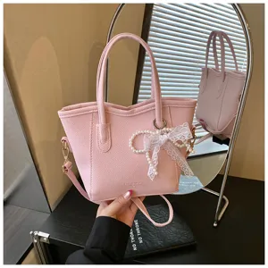 Pink PU leather bucket handbag detailed view, featuring elegant pearl lace bow pendant and top handles.