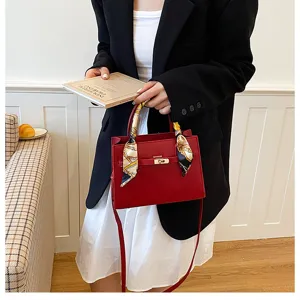 Detailed view of women's red leather handbag with elegant scarf detail and gold hardware.