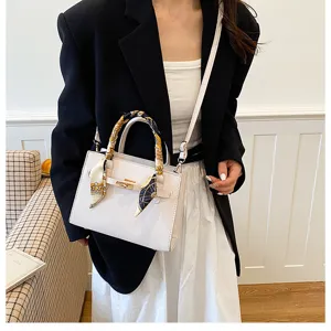 Close-up shot of stylish white women handbag featuring elegant turn-lock and scarf detail.