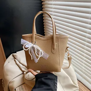 Trendy commuter bucket bag for women with pearl bow pendant, large capacity casual solid color tote.