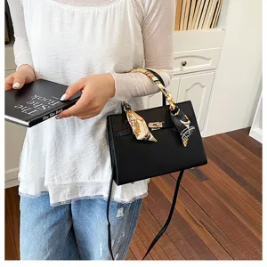 Classic black leather handbag with stylish printed scarf handle and metal lock closure.