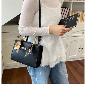 Elegant black leather handbag for women, stylish tote bag with chic scarf and metal lock.