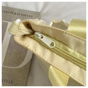 Close-up detail of the light yellow canvas tote bag featuring secure zipper closure and durable handles.