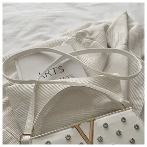 Vue détaillée du sac à bandoulière blanc avec logo V métallique et strass scintillants.