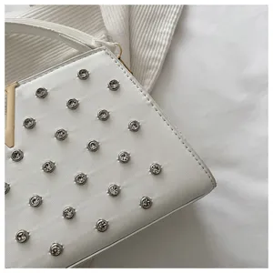 Gros plan détaillé d'un sac à main blanc tendance orné de strass scintillants et de détails dorés.