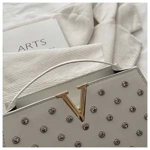 Sac à main blanc élégant en cuir, design chic avec logo V en métal et clous scintillants.