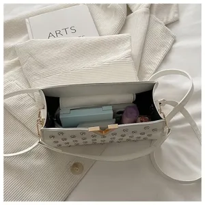 Vue détaillée d'un sac bandoulière blanc à clous avec fermoir design et espace de rangement.