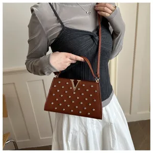 Détail en gros plan d'un sac à main marron avec strass et boucle métallique en V élégante.