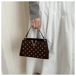 Détail du sac à main marron avec des strass étincelants et une fermeture métallique en V.