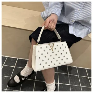 Gros plan détaillé d'un sac à main blanc chic avec des rivets métalliques et un logo V doré.
