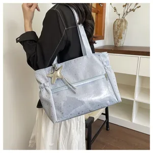 Vista dettagliata della grande borsa a tracolla azzurra con stampa di stelle e ciondolo.