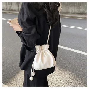 Vue de détail d'un sac seau blanc chic avec cordon de serrage porté, style urbain élégant.