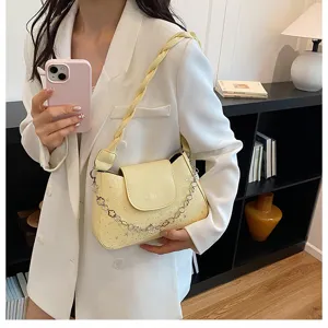 Chic light yellow shoulder bag with star pattern, braided strap and elegant chain detail.