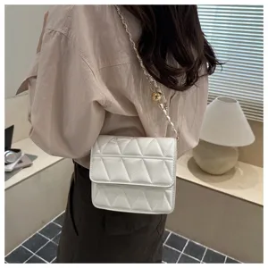 Detailed view of white quilted crossbody bag with stylish chain strap and modern interior background.