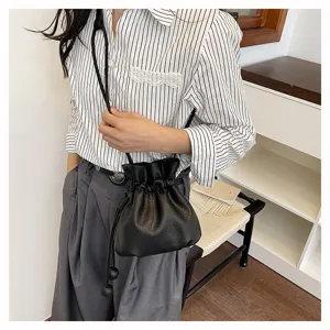 Gros plan detaille du sac seau noir en cuir avec cordon de serrage et bandouliere fine.