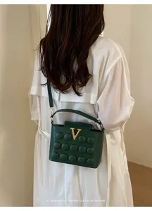 Vista dettagliata della borsa a tracolla verde scuro effetto bolla con fibbia V.