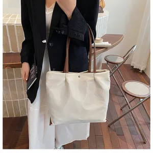 Detailed view of a minimalist white commuter tote bag featuring stylish brown straps in a chic setting.