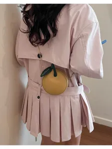 Close-up detail of the cute yellow apple-shaped crossbody bag with green leaf tag and chain.