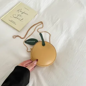 Detail shot of a cute mini yellow apple-shaped crossbody bag with green leaf and chain strap.