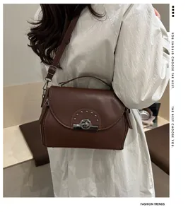 Vue détaillée d'un sac bandoulière en cuir marron rétro avec serrure en métal et rivets.