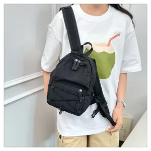 Detailed view of a mini black casual backpack featuring a front elastic cord and zippers.