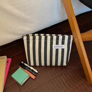 Trousse de maquillage rayée noir et blanc en toile, pochette de rangement de voyage en détail.