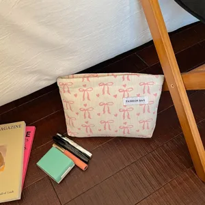 Détail de trousse de maquillage en velours côtelé avec motif nœuds roses, grand rangement.
