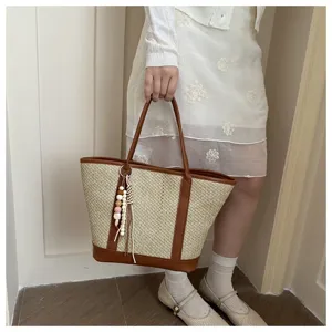 Women straw woven tote bag summer beach shoulder bag with brown leather trim and cute bead pendant.