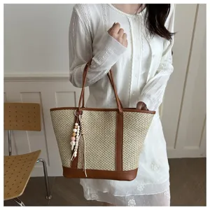 Chic summer straw tote bag with brown PU leather trim and cute beaded charm detail in a scene.