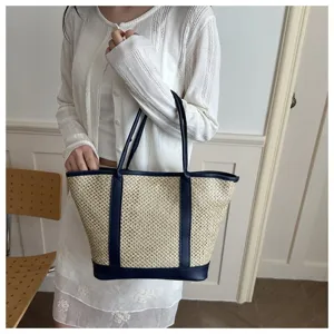 Detailed shot of women's summer straw woven shoulder bag with blue leather trim and dual handles.