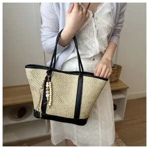 Detailed shot of a stylish summer straw woven tote bag with chic wooden bead pendant.
