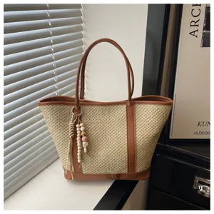 Woven straw tote bag detail, summer beach shoulder bag with PU leather trim and charming pendants.