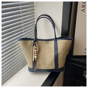 Woven straw shoulder bag detail, stylish navy blue leather trim with wooden bead charm.