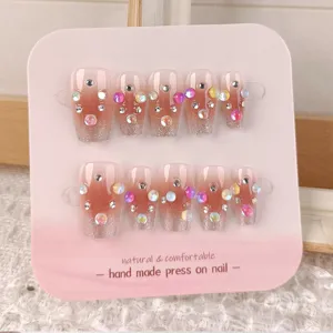 Uñas postizas hechas a mano con degradado rubor, purpurina plateada y pedrería de colores.