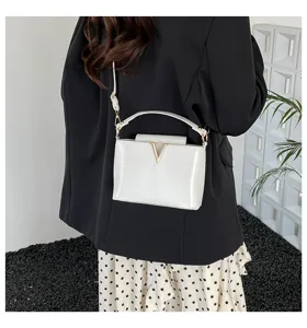 Élégant sac seau bandoulière blanc avec logo V métallique, sac à main femme chic.