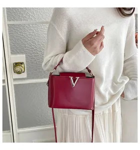 Sac à bandoulière seau élégant rouge avec logo V en métal, sac à main tendance pour femmes.