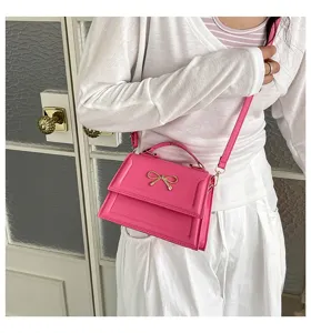 Vue détaillée d'un sac à bandoulière rose chic avec un nœud doré élégant et sangle.