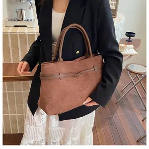 Detail view of retro brown suede tote bag styled with black blazer in cafe setting.