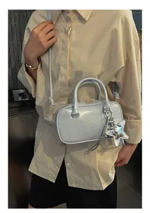 Detail shot of light blue patent leather Boston handbag with silver star charm and crossbody strap.