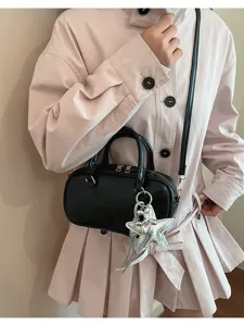 Black patent leather Boston handbag detail showing cross-body strap and star keychain charm.