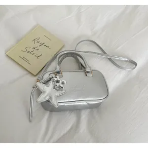 Silver metallic boston handbag detail with star pendant, glossy finish and dual handles.