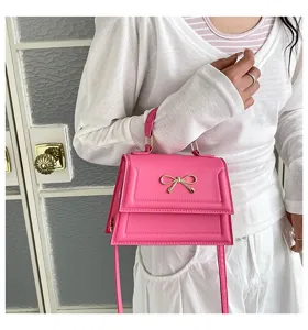 Gros plan d'un sac à main rose pour femme avec un joli nœud en métal et une poignée.