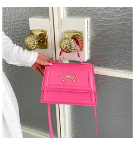 Détail du sac bandoulière rose avec nœud, montrant les superbes finitions et ferrements dorés.