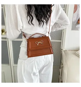 Sac bandoulière marron élégant pour femme avec nœud doré chic et poignée supérieure.