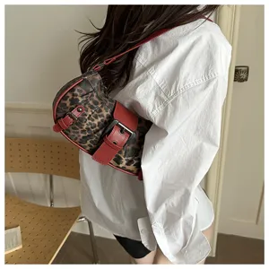 Detalle de bolso de hombro con estampado de leopardo, correa con hebilla roja y textura.