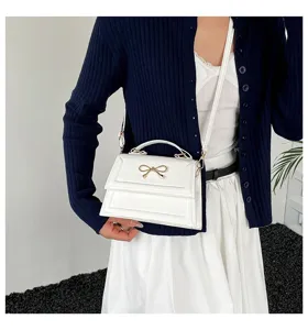 Vue détaillée du sac à main blanc tendance avec un nœud doré chic et une bandoulière.