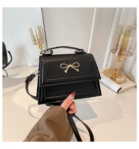 Gros plan détaillé de l'élégant sac à main noir doté d'un nœud doré chic et raffiné.