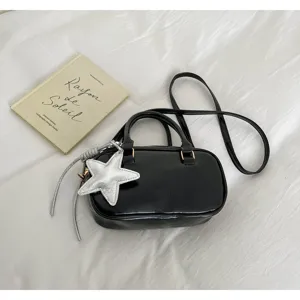 Stylish black patent leather Boston handbag with silver star pendant and crossbody strap.