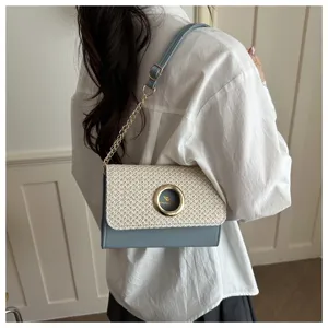 Détail de élégant sac à épaule en paille avec cuir bleu et boucle ronde dorée pour femmes.